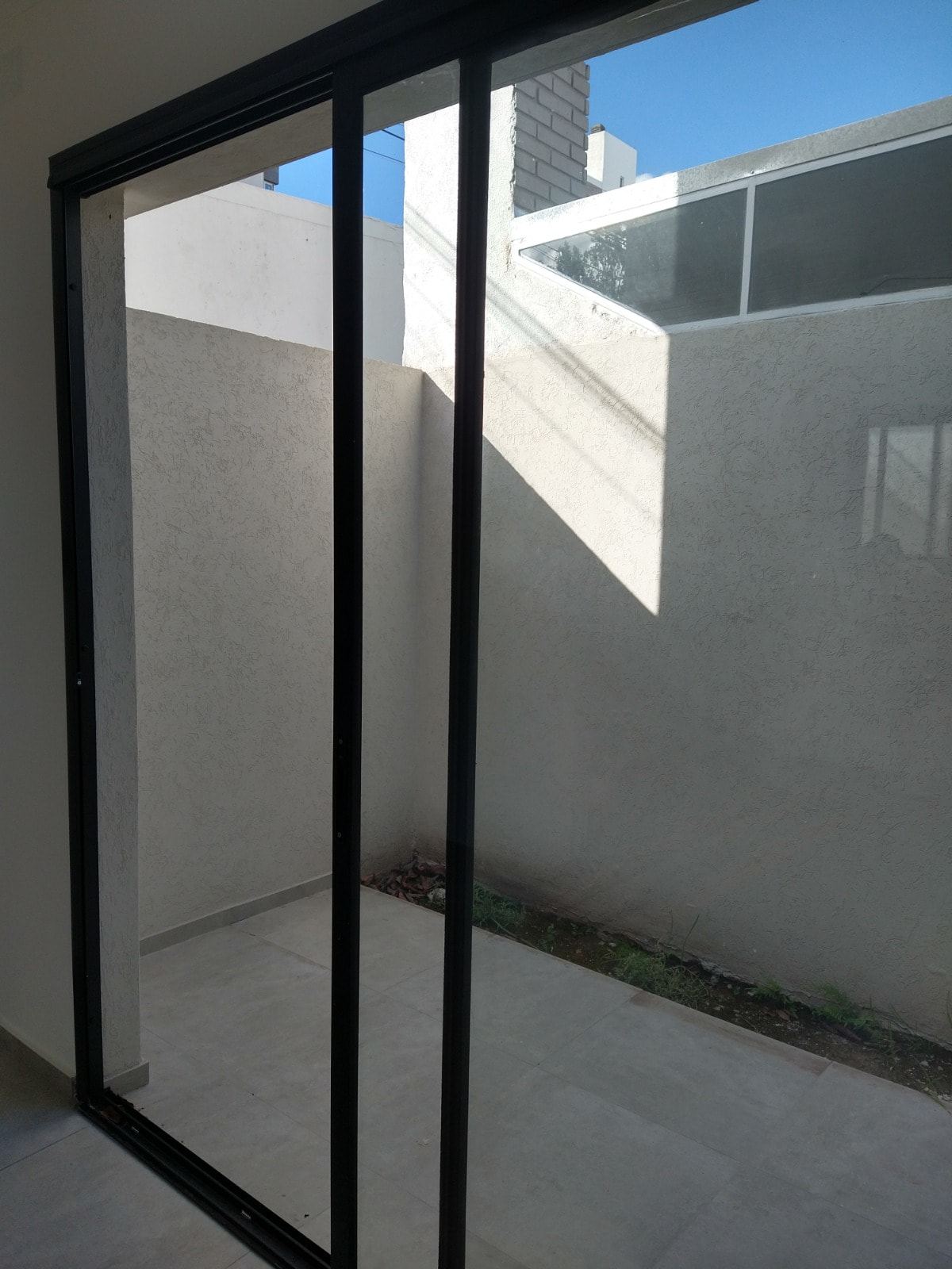 Photograph of the courtyard before the works: open to the sky, plastered walls and a window.