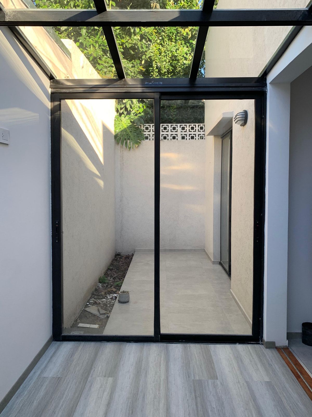 Site photograph of the enclosed courtyard with a glass roof and black sliding frames.